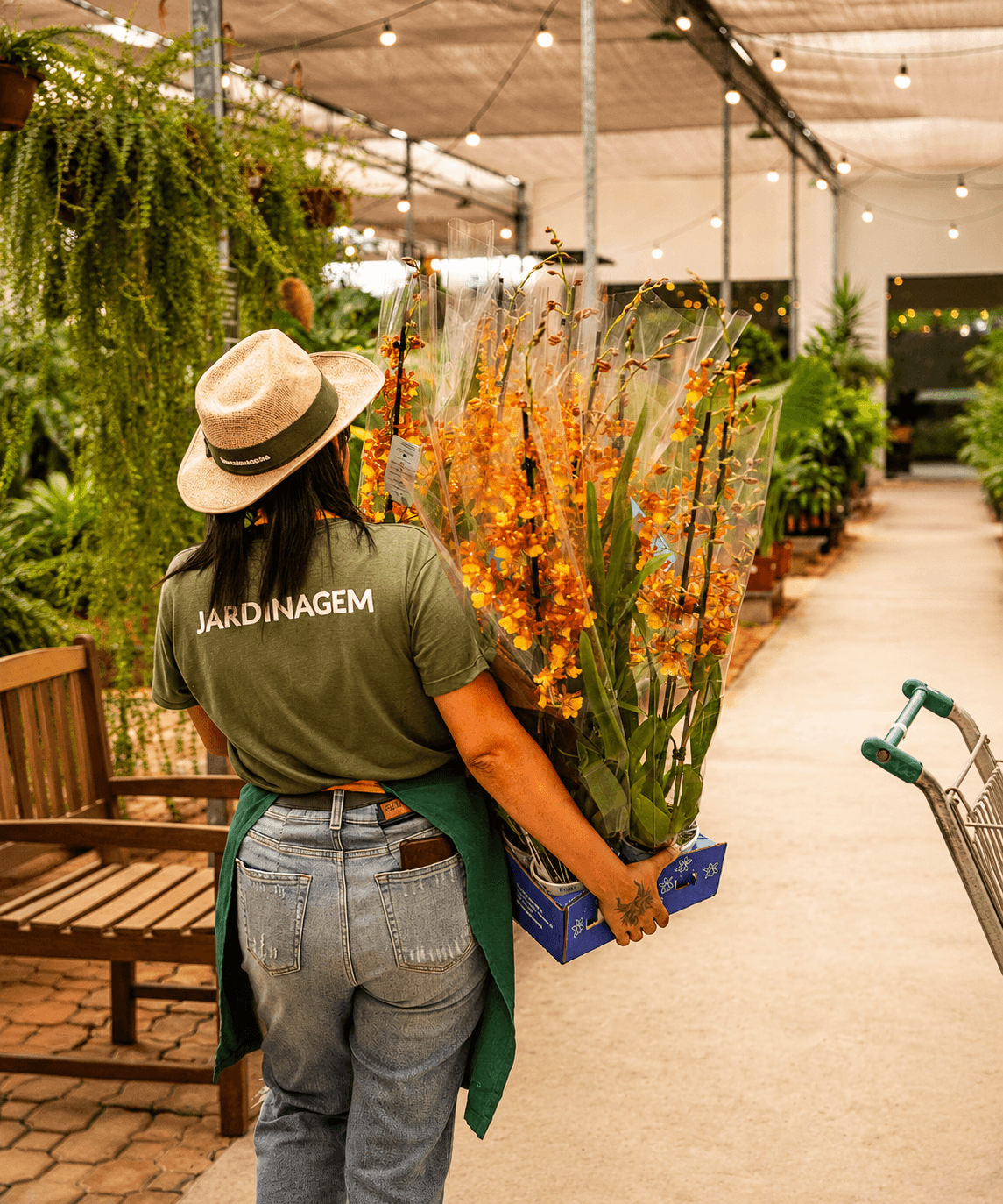 Integrante da equipe do Horto das Acácias entre vasos e mudas floridas